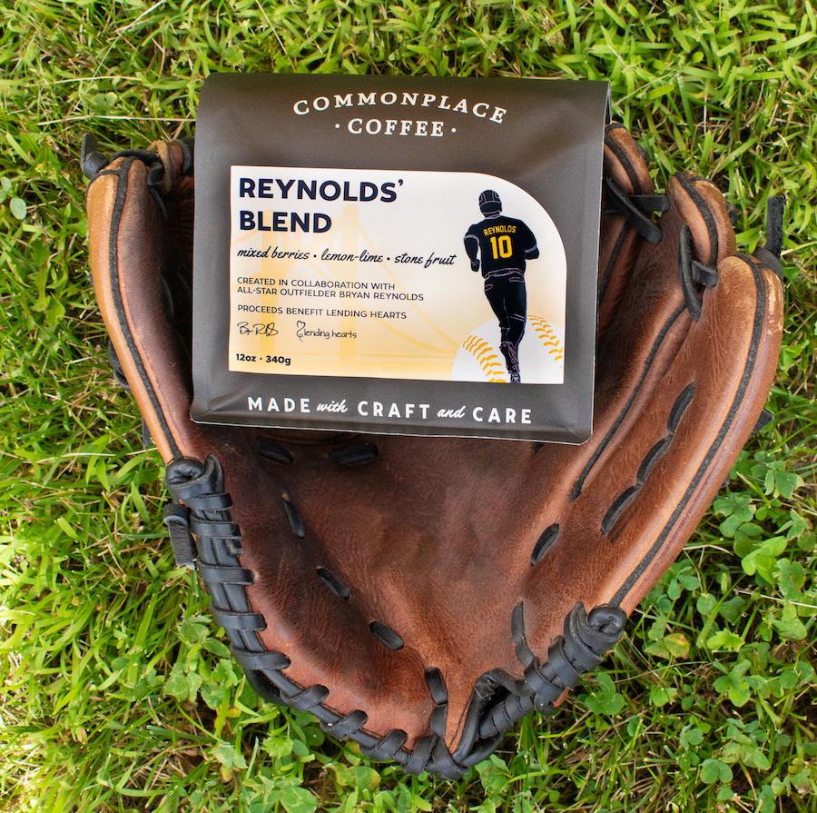 A bag of Reynolds' Blend coffee sits in a brown leather baseball mitt laying on a green lawn.